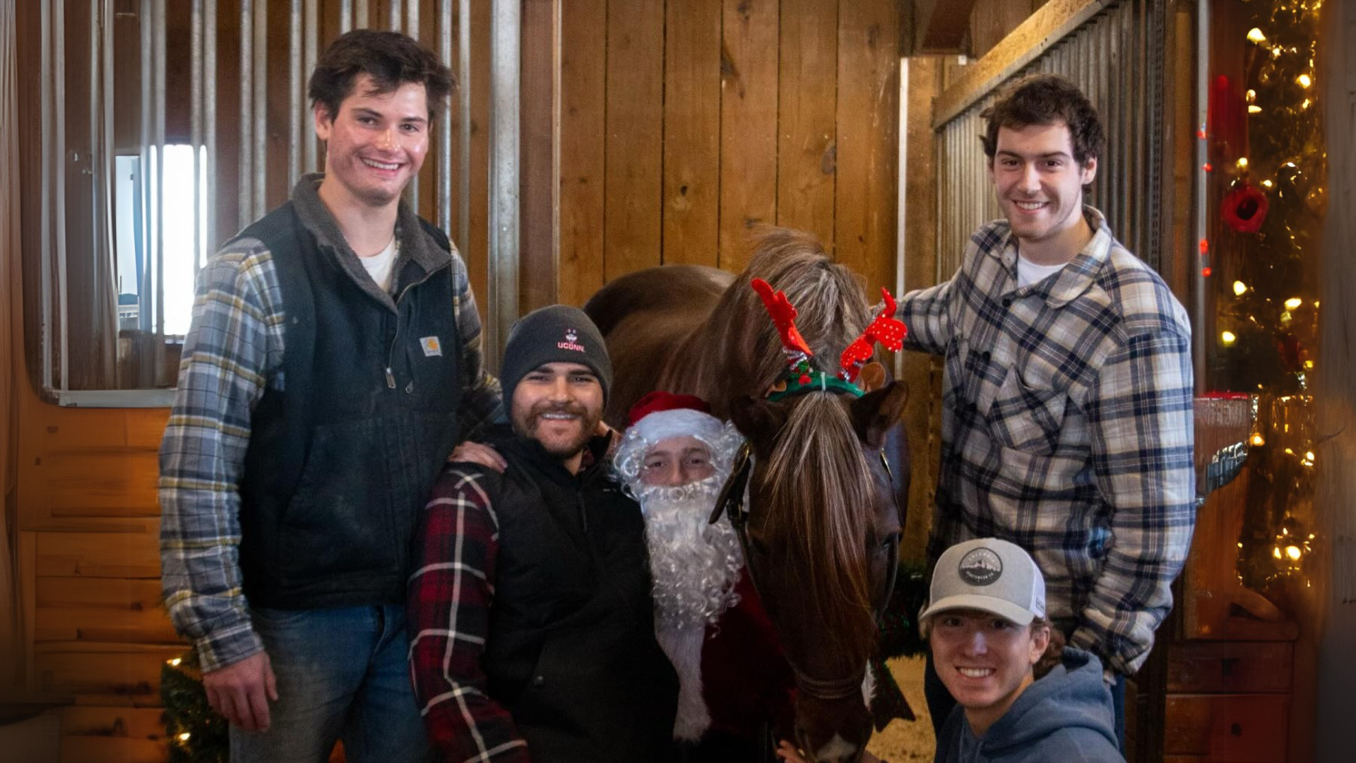 Group posing for photo with horse in front of stall.