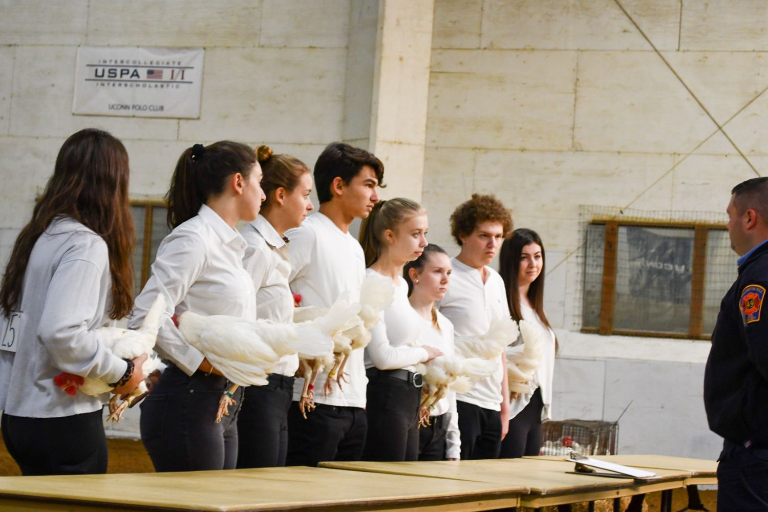 Students holding up chickens for judging competition in arena