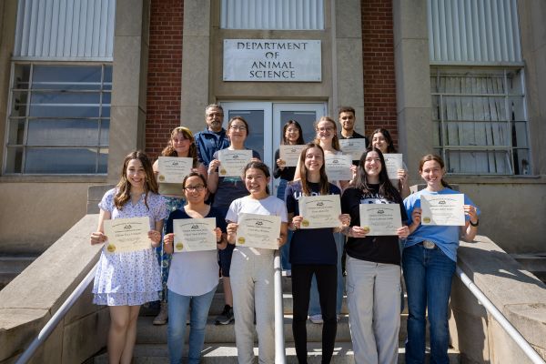 A group of students holding their award certificates on a staircase outside of the George White Building