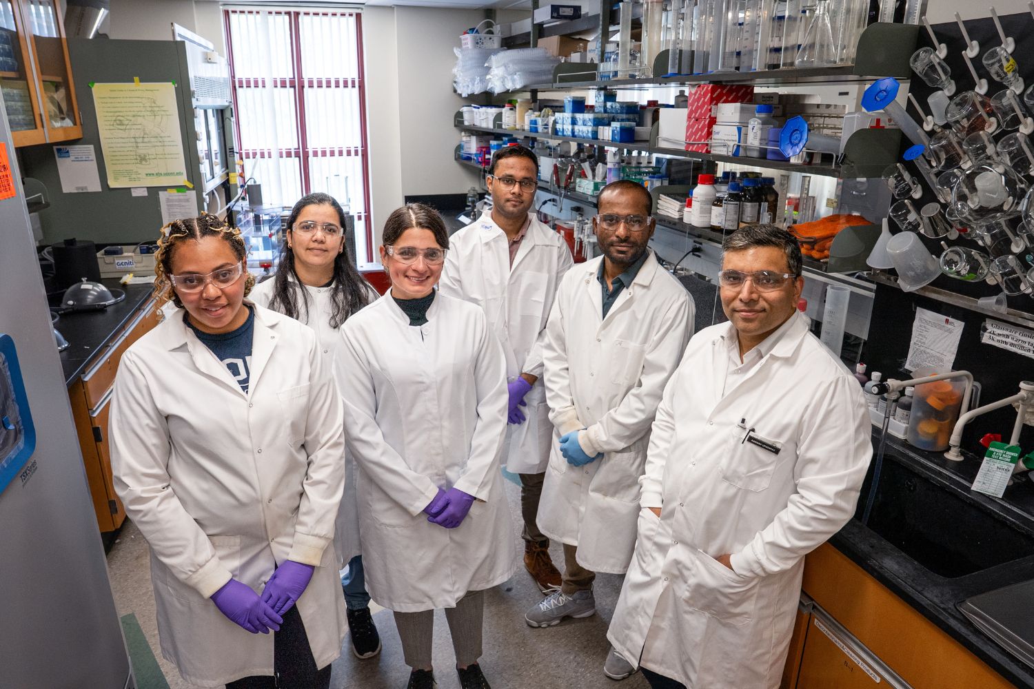A group of individuals dressed in lab attire posing for a photo.