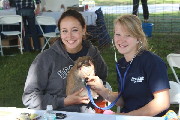 Two women holding a dog at a table.