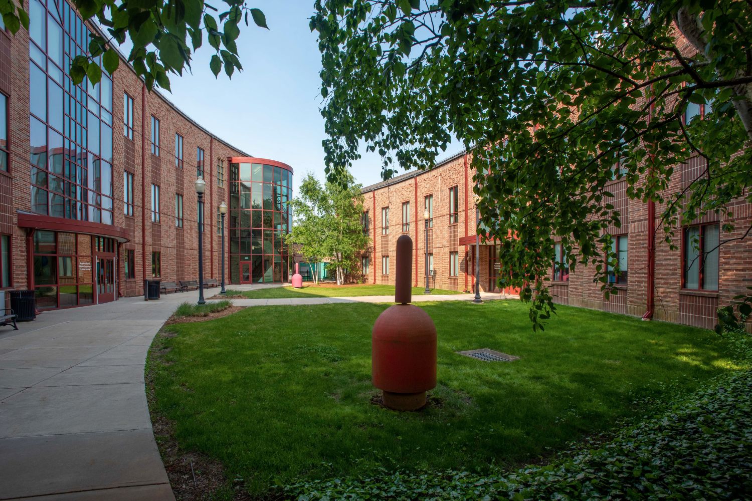 A grass landscape stretched between 2 curved red brick buildings.