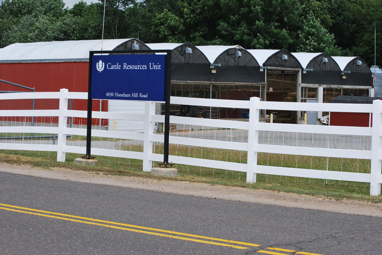 A red barn sitting behind a white fence.