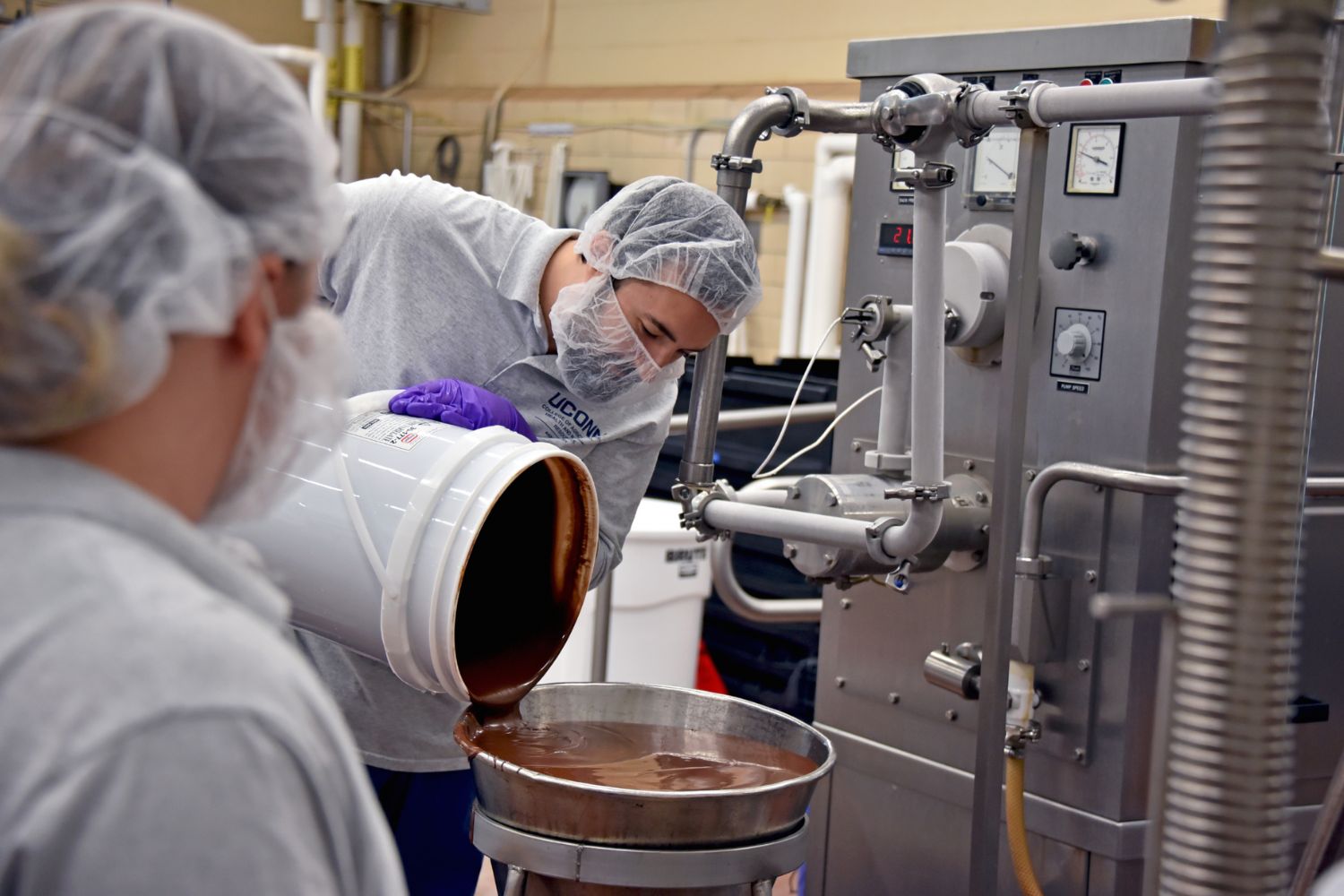 A man pouring a brown liquid into a machine.