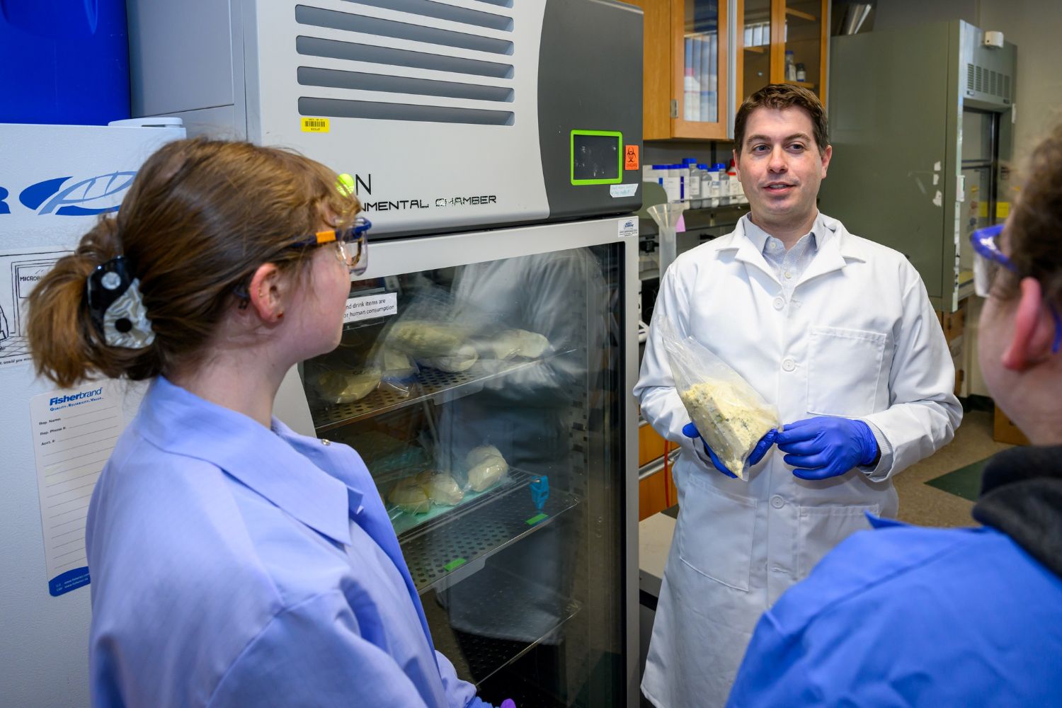 A man in a lab coat conversing with other researchers. 