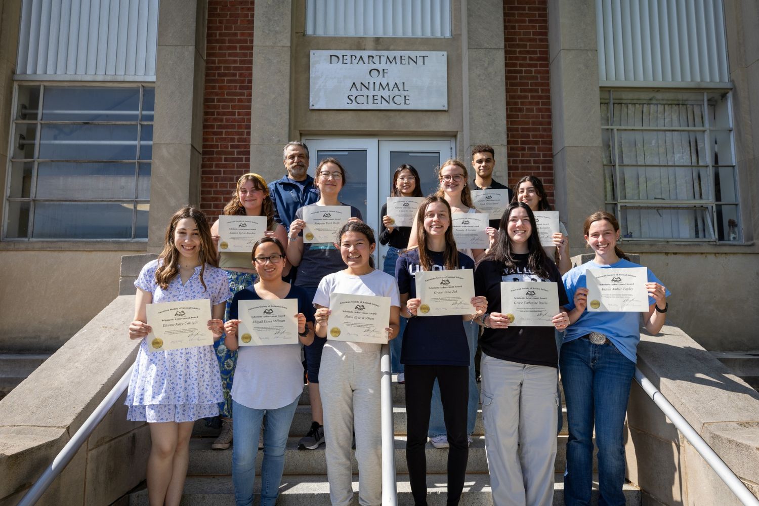 A group of individuals holding certificates on a staircase.
